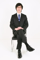 흰 배경 스튜디오에 앉아있는 비즈니스맨