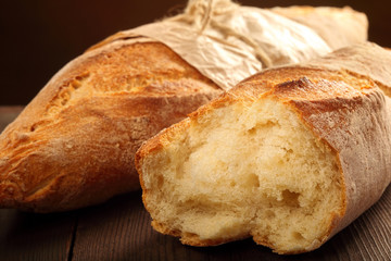 French baguettes in paper on wooden background