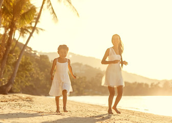 Mother and daughter happily running along the beach, Thailand