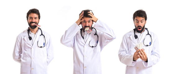 Surprised doctor holding pills over white background