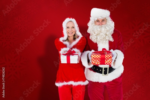 Santa And Mrs Claus Smiling At Camera Offering Gift Santa And Mrs Claus Smiling At Camera Offering Gift
