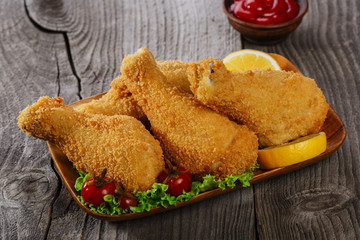 fried chicken leg in breadcrumbs on a wooden surface
