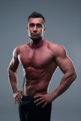 Fototapeta na wymiar Portrait of a muscular sportsman posing over gray background