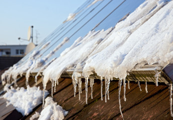 snowy solar panels on the roof of a house © milkovasa