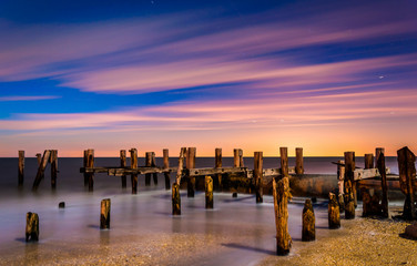 Ruins of an old pier on Sunset Beach at night, in Cape May, New - Powered by Adobe