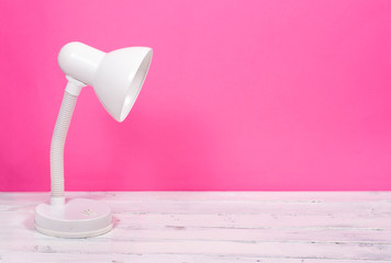 White lamp on white wood desk on pink background