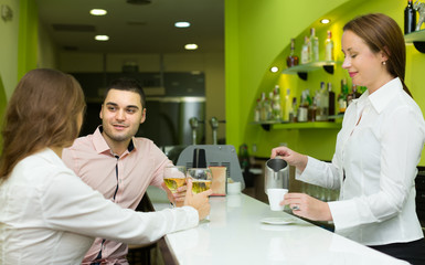 Female barista and two clients in cafe