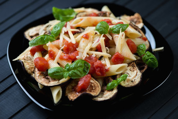 Pasta alla Norma on a black glass plate, horizontal shot