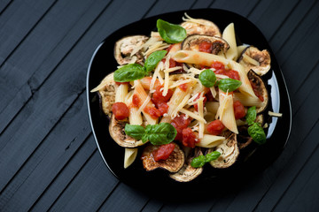 Pasta alla Norma over black wooden background, high angle view