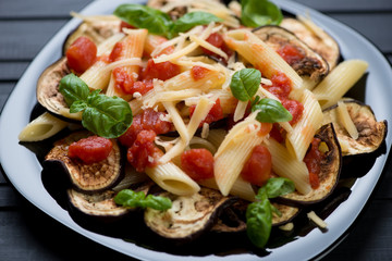 Black glass plate with pasta alla Norma, close-up, studio shot