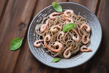 Soba noodles with shrimps over rustic wooden background