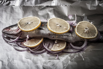Fish prepared for roasting on the foil with lemon and onion