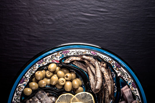 Assorted fish on a plate on a dark background. With space for te