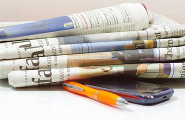 Tageszeitung mit Handy und Kugelschreiber