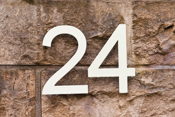 Hausnummer 24 in weiss an einer Natursteinmauer