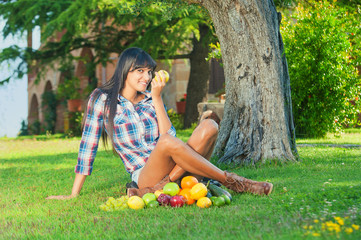 Beautiful woman on the green grass eaten fruits