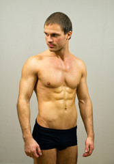 Fototapeta premium Muscular male model posing on grey background.