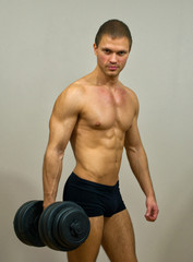 Fototapeta na wymiar Handsome muscular male model with dumbbell.