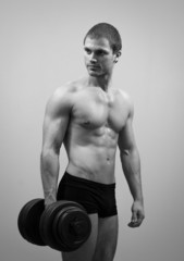 Fototapeta na wymiar Handsome muscular male model with dumbbell. Black and white.