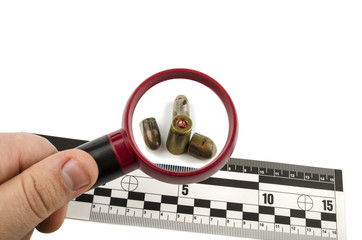 bullets and shell under a magnifying glass with a line of forens