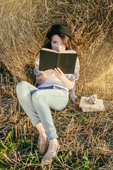Naklejka na ściany i meble girll hipster reads book against hay bale in fall