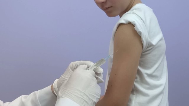 The doctor prepares an injection for a young patient