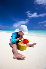 Boy drinking coconut water on tropical island beach with blue la