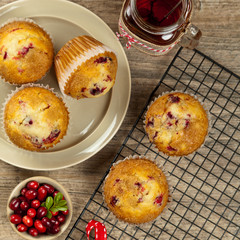 Muffins with cranberry on cooling rack on wooden background.