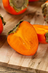Delicious orange persimmons on wooden table. Selective focus.