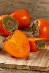 Delicious orange persimmons on wooden table. Selective focus.