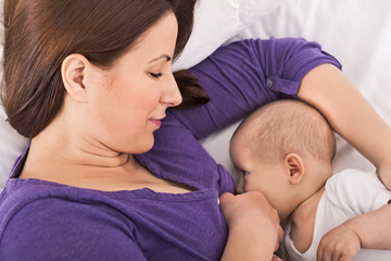 Fototapeta na wymiar Smiling happy mother breastfeeding her baby infant