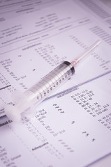 A stethoscope on the top of a blood test result, dark tone