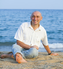 Naklejka na ściany i meble man sitting on sandy beach
