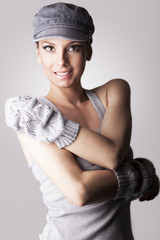 Beautiful woman with cap and gloves, on gray background - obrazy, fototapety, plakaty