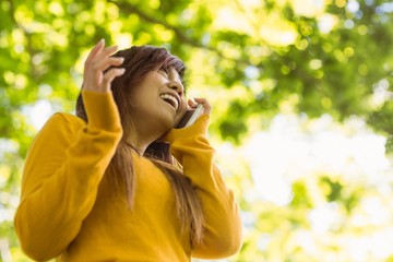 Cheerful woman using mobile phone in park