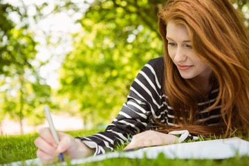 Naklejka na ściany i meble Female student doing homework in park