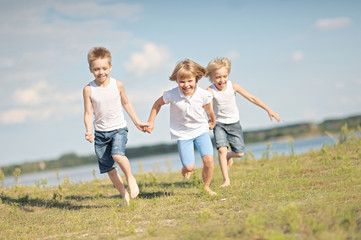 Fototapeta premium three children playing on meadow in summer