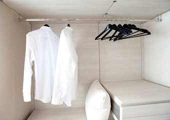 white shirts hanging on built-in cloths racks, with drawers and