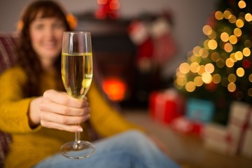 Redhead holding glass of champagne on couch at christmas