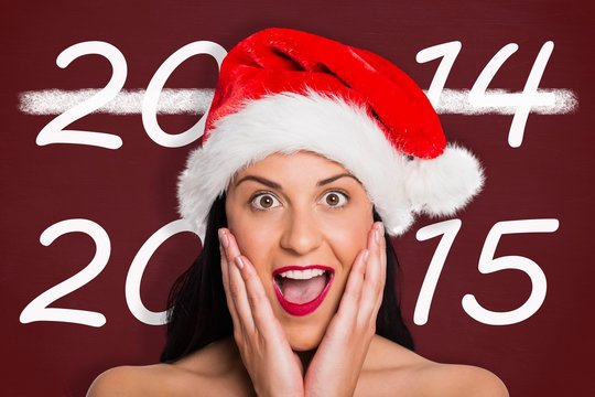 Composite image of surprised woman wearing santa hat