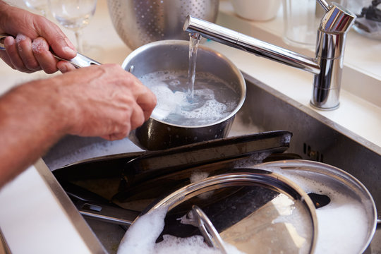 Close Up Of Man Washing Pans In Sink