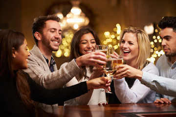 Group Of Friends Enjoying Evening Drinks In Bar - obrazy, fototapety, plakaty