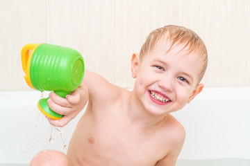 The beautiful little boy bathes in a blue bath with a toy