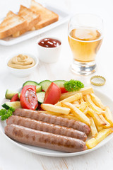 grilled sausages with French fries, vegetables and glass of beer