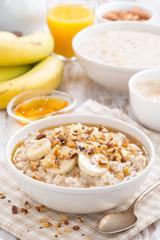 oatmeal with banana, honey and walnuts in bowl for breakfast