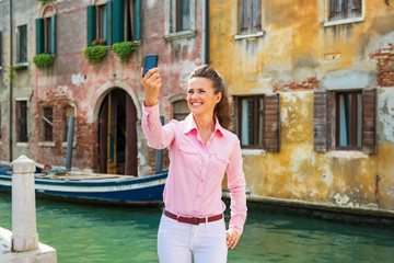 Fototapeta na wymiar Happy young woman making selfie in venice, italy