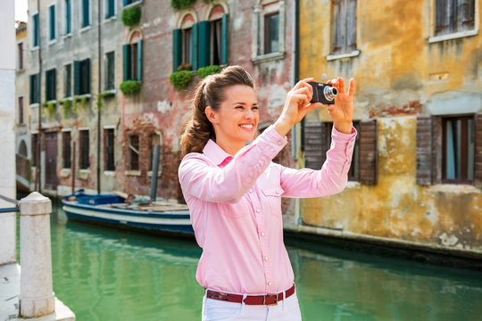 Happy young woman taking photo in venice, italy