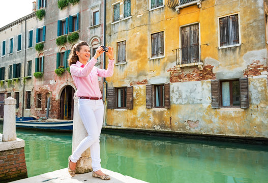 Full length portrait of happy young woman taking photo in venice