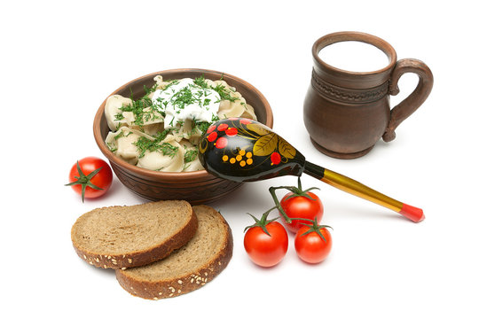Russian dumplings in a clay bowl, bread, milk and tomatoes on a