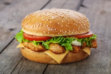 Fototapeten hamburger with chicken and cheese on a wooden surface © koss13